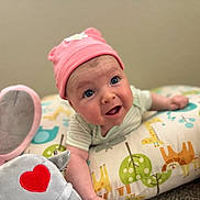 Shia joined the competition — help win amazing prizes! baby, infant, pink_hat, plush_toy, elephant_toy, heart_patch, colorful_pillow, animal_print, giraffe, lion, green_leaves, blue_bird, striped_clothing, cute, expression, indoors, soft_toys, child, face, curious