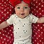 baby, infant, red_bow, headband, white_onesie, blue_stars, star_pattern, red_blanket, lying_down, wide_eyes, surprised_expression, cute, adorable, child, portrait, face, skin, person, young_child, happy