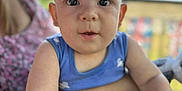 Sonny is registered to the contest to win money with this photo: baby, child, person, face, eyes, arm, skin, blue_clothing, outdoor, daylight, adult, blurred_background, curious, infant, portrait, closeup, cute, expression, young, sitting
