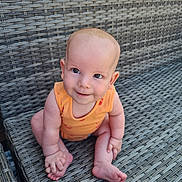 Sonny joined the competition — help win amazing prizes! baby, child, infant, orange_clothing, sitting, woven_chair, outdoor_furniture, smiling, cute, playful, barefoot, skin, eyes, head, hand, foot, person, young, happy, portrait