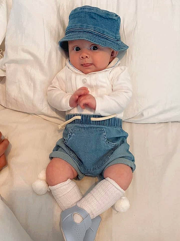 Harlan is registered to the contest to win money with this photo: baby, baby_toddler_clothing, cap, comfort, cool, eye, face, finger, hand, headgear, headwear, knee, person, skin, sleeve, sock, sun_hat, textile, thigh, toddler