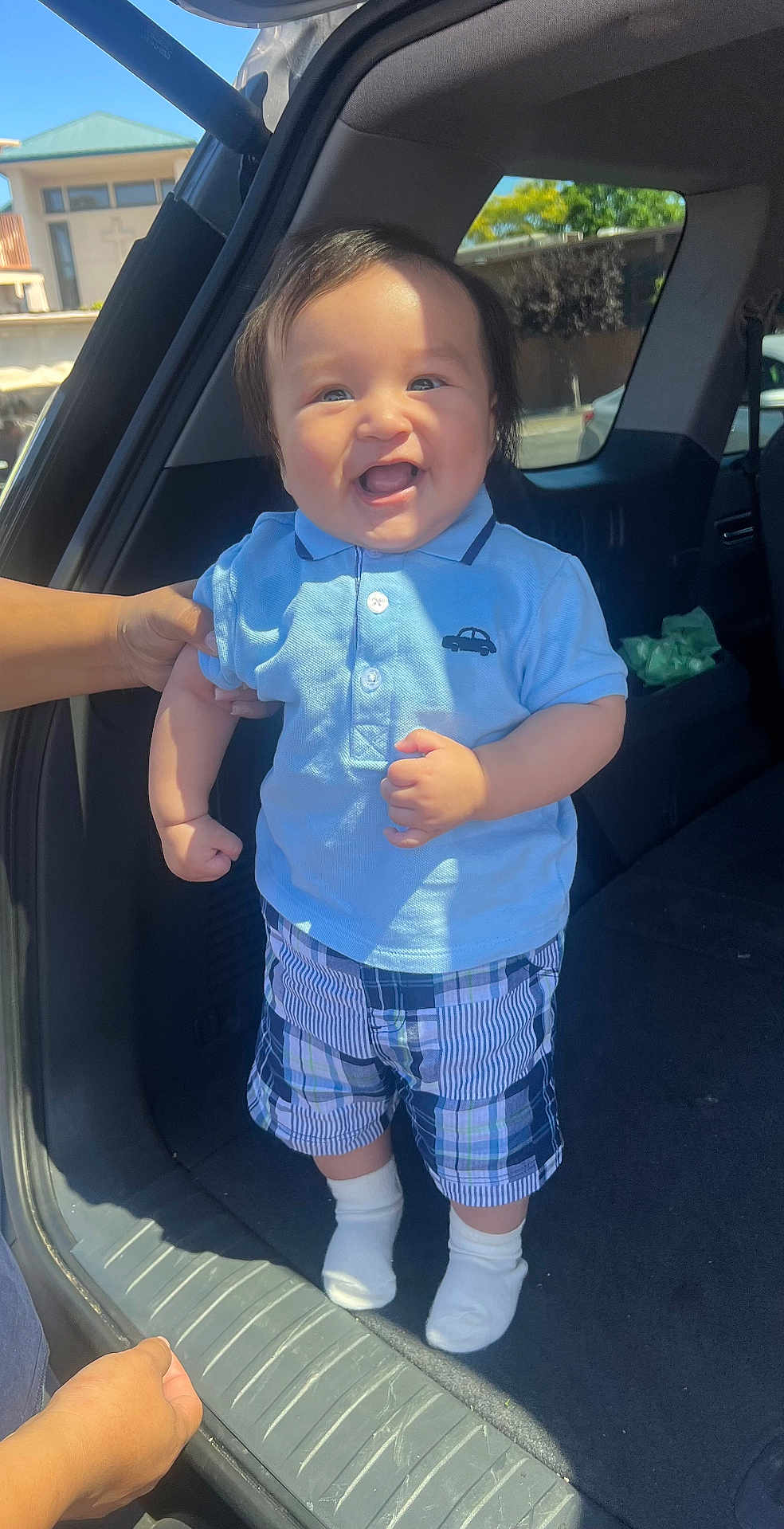 Uvaldo Jr joined the competition — help win amazing prizes! baby, child, toddler, smiling, blue_shirt, plaid_shorts, socks, car, car_trunk, hand, sunlight, outdoor, happy, clothing, person, cute, standing, portrait, daylight, human