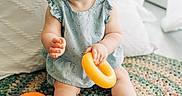 Margaret joined the competition — help win amazing prizes! baby, child, blue_eyes, headband, pink_bow, ring_toy, smiling, sitting, colorful_rug, pillow, indoor, playtime, cute, happy, toys, infant, clothing, soft_light, portrait, floor