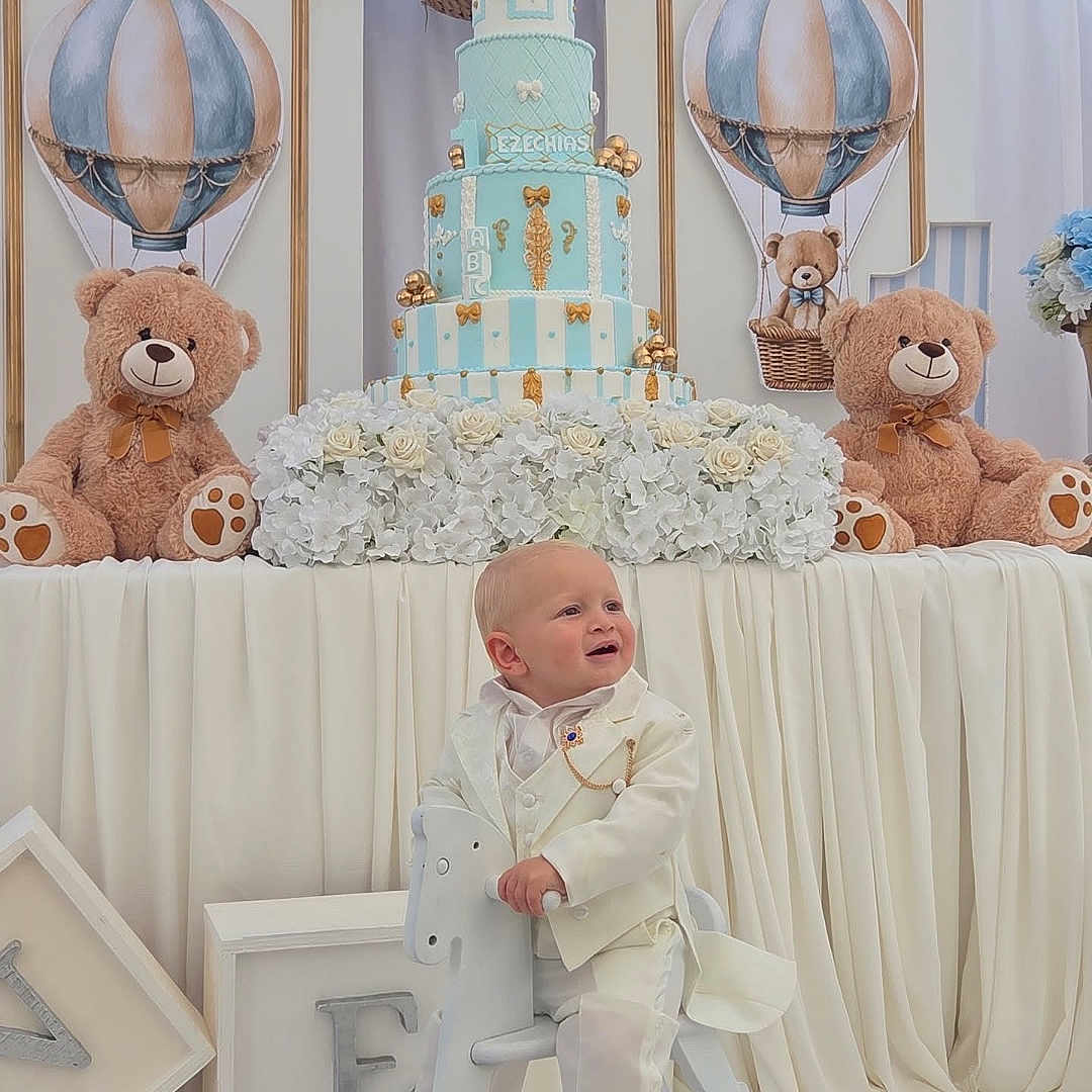 Ezéchias a rejoint le concours — aidez-le/la à gagner de superbes lots ! balloons, birthday_cake, blue, celebration, child, cream, decorations, festive, flowers, formal_wear, happy, indoor, party, rocking_horse, smiling, teddy_bear, toddler, white_background, white_suit, wooden_toy