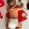 baby, back_view, balloon, black_thread, bracelet, cute, decor, diaper, flower, handmade_flower, infant, lipstick_marks, love_theme, lying_down, pillow, red_heart, skin, sleeping_position, toddler, white_sheet