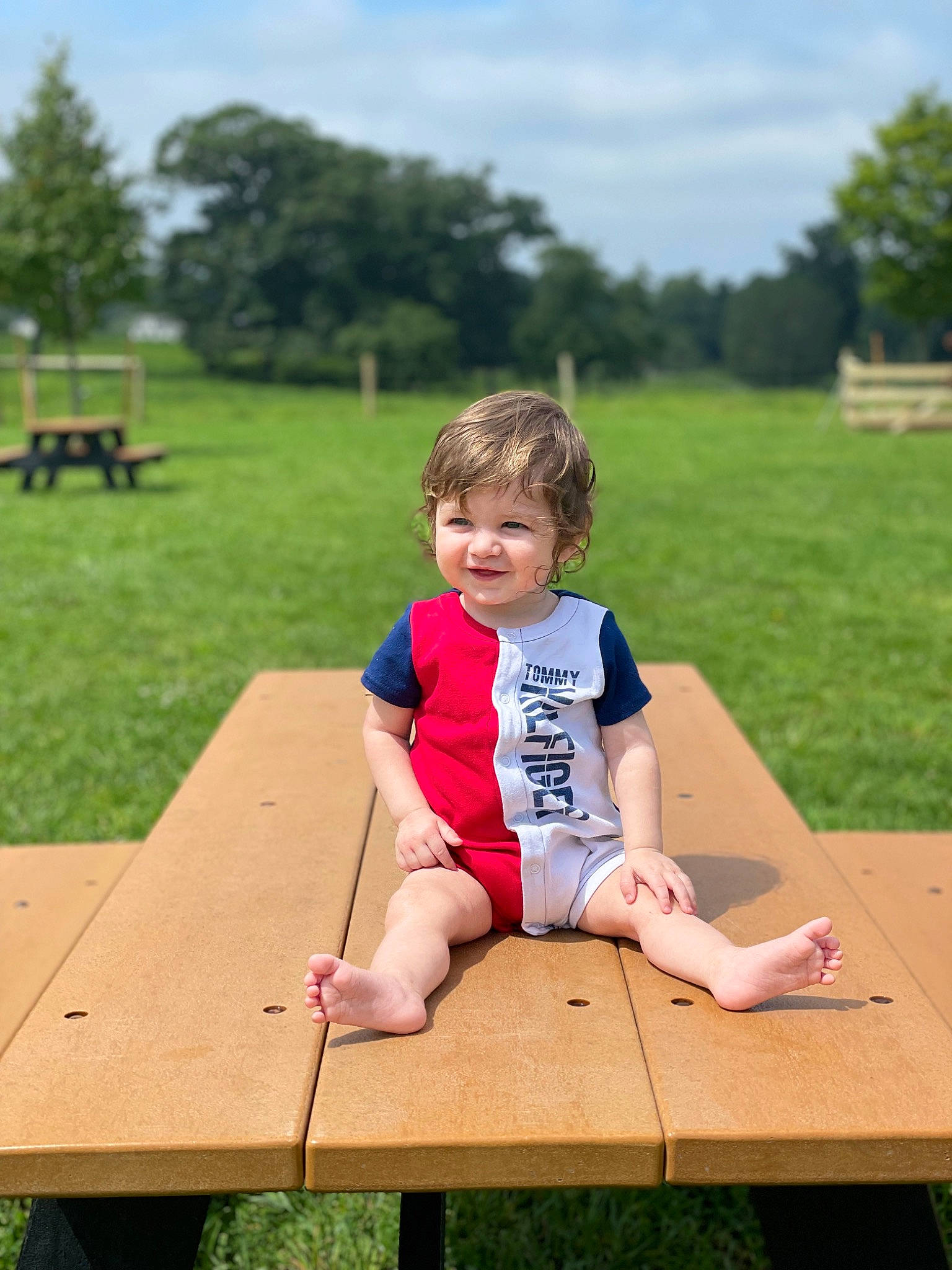 Brayden is registered to the contest to win money with this photo: baby_toddler_clothing, cloud, fun, grass, happy, joy, leg, leisure, outdoor_furniture, outdoor_play_equipment, people_in_nature, person, plant, recreation, shorts, skin, sky, summer, table, toddler