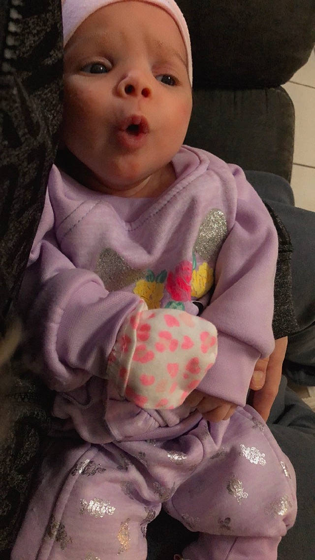 Haiden is registered to the contest to win money with this photo: baby, baby_toddler_clothing, cheek, child, dress, eye, face, facial_expression, happy, head, human, human_body, iris, lip, mouth, nose, person, pink, purple, skin