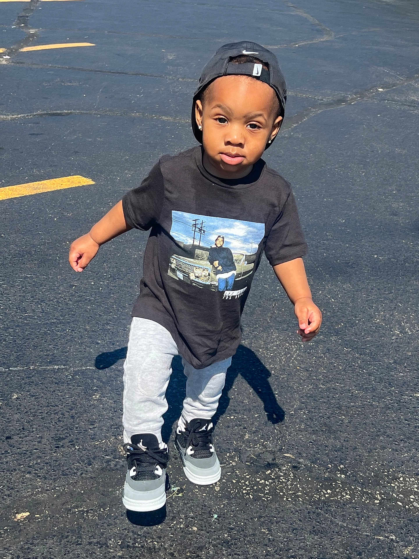Michael joined the competition — help win amazing prizes! toddler, child, boy, cap, backwards_cap, tshirt, graphic_tee, sneakers, pants, outdoor, asphalt, shadow, sunlight, walking, street, cute, fashion, casual, young, person