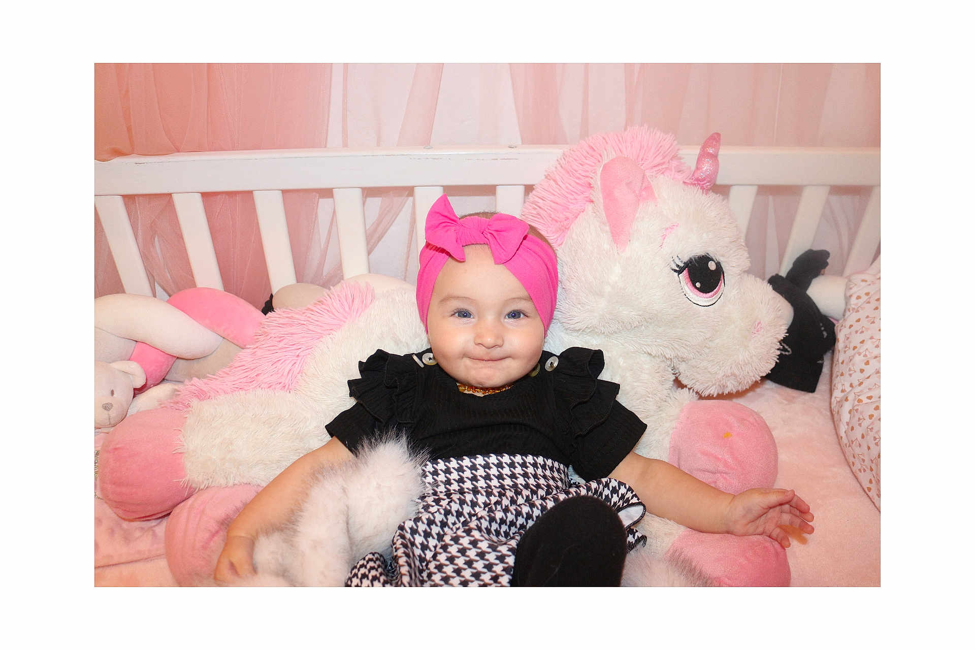 Elya participe au concours pour gagner de l'argent avec cette photo : baby, black_top, blanket, child, clothing, crib, cute, happy, headband, indoors, infant, patterned_skirt, pink, pink_bow, plush_toy, smile, soft_toy, toddler, unicorn, white