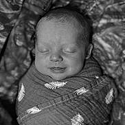 Asher is registered to the contest to win money with this photo: baby, newborn, swaddled, blanket, sleeping, smiling, face, infant, wrapped, cozy, cute, peaceful, soft, portrait, child, monochrome, black_and_white, young, resting, adorable