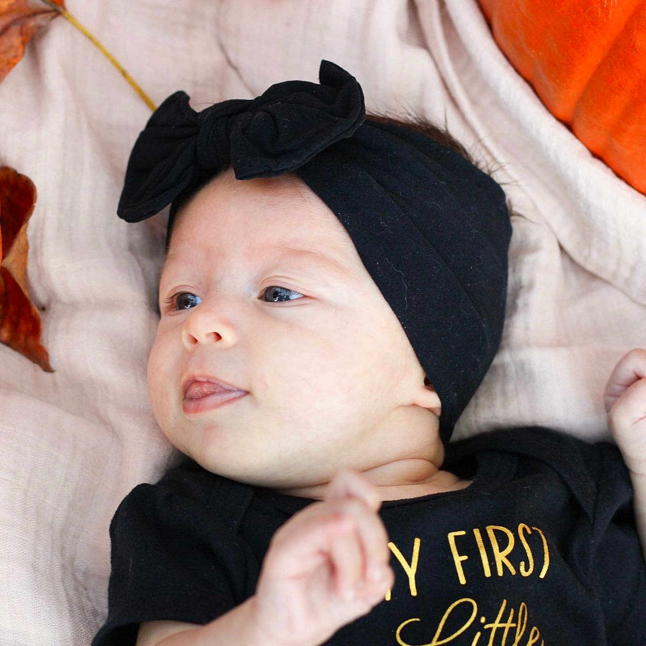 Lillianna is registered to the contest to win money with this photo: autumn_leaves, baby, black, black_clothing, blanket, bow, child, cute, fall, headband, infant, lying_down, orange, playful, portrait, pumpkin, seasonal, skin, soft_texture, tongue_out
