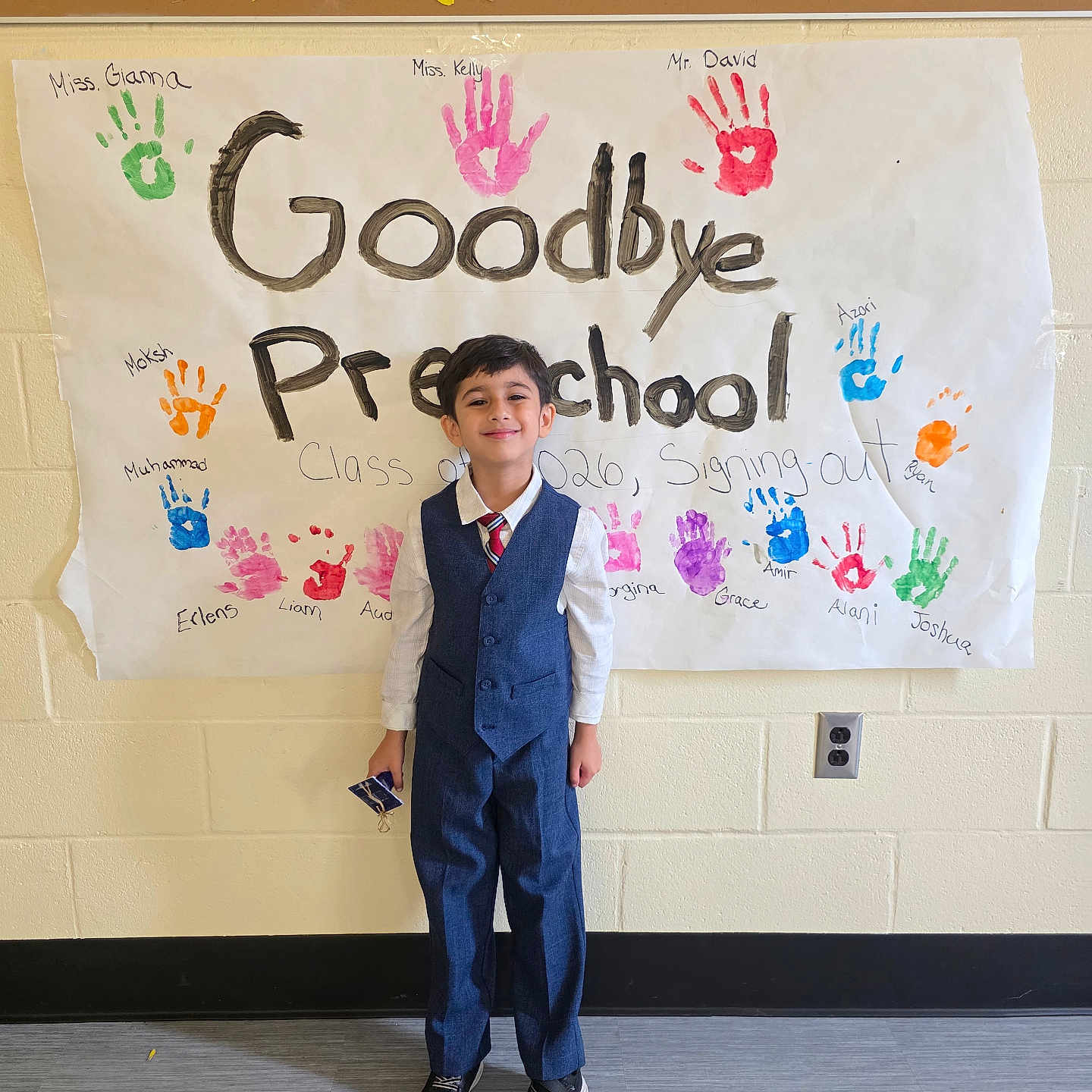 Muh joined the competition — help win amazing prizes! child, boy, preschool, graduation, banner, handprints, colorful, wall, clothing, vest, tie, shoes, smile, indoor, school, celebration, person, standing, floor, background