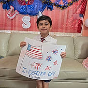 Muh joined the competition — help win amazing prizes! child, boy, independence_day, american_flag, poster, celebration, holiday, festive, decorations, sofa, home_interior, carpet, smiling, shorts, shirt, tie, fireworks, patriotic, handmade_sign, happy