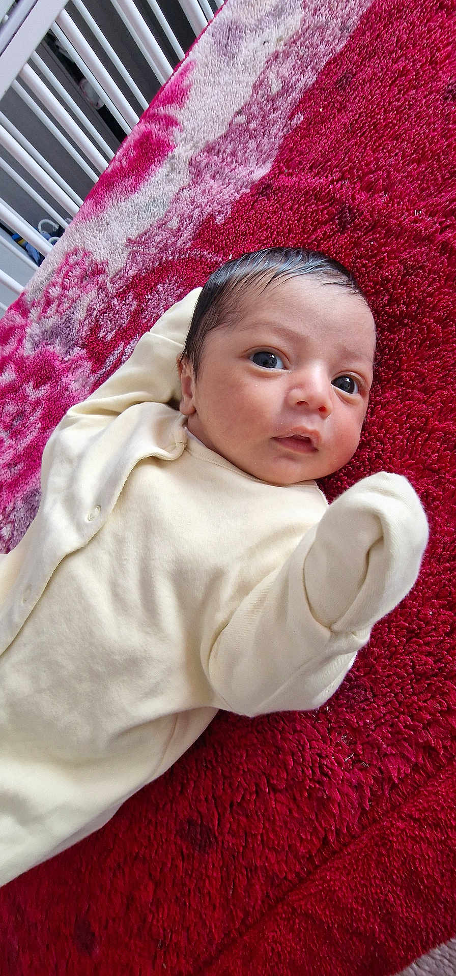 Yazen joined the competition — help win amazing prizes! baby, infant, blanket, red, pink, face, clothing, laying_down, crib, bedroom, newborn, cute, person, skin, head, expression, indoors, soft_texture, young_child, portrait
