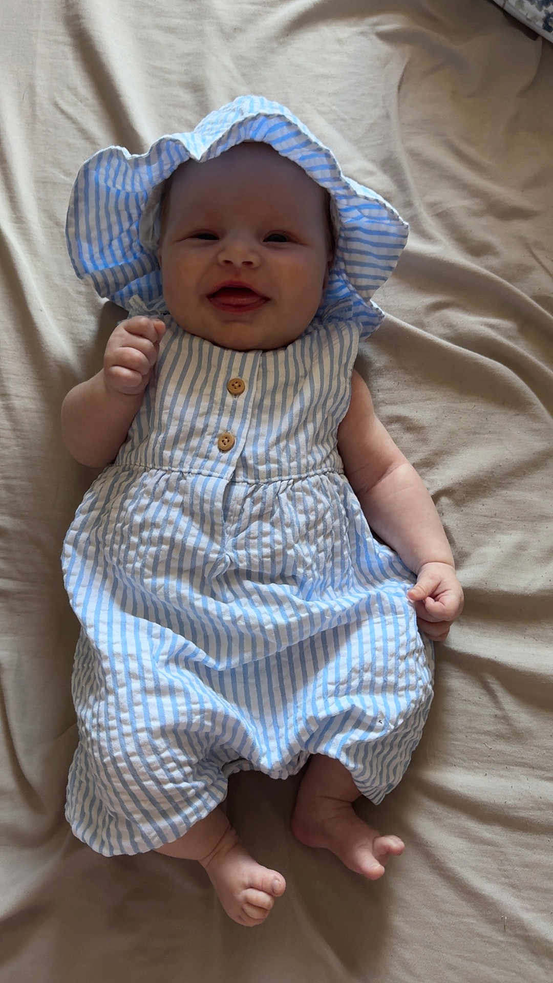 Freya Rose joined the competition — help win amazing prizes! baby, infant, smiling, blue_stripes, hat, cute, lying_down, blanket, clothing, fist, happy, child, foot, toes, portrait, one_person, indoors, apparel, headwear, skin