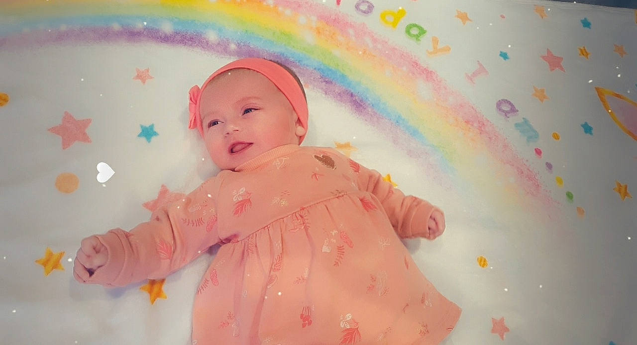 Maëlia participe au concours pour gagner de l'argent avec cette photo : baby, baby_laughing, baby_toddler_clothing, bonnet, cheek, child, colorfulness, headwear, hood, peach, person, pink, rainbow, skin, sleeve, sweetness, toddler