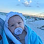 baby, pacifier, towel, beach, sky, cloud, pier, hat, infant, child, blue, white, outdoor, sand, person, portrait, headwear, closeup, blanket, summer