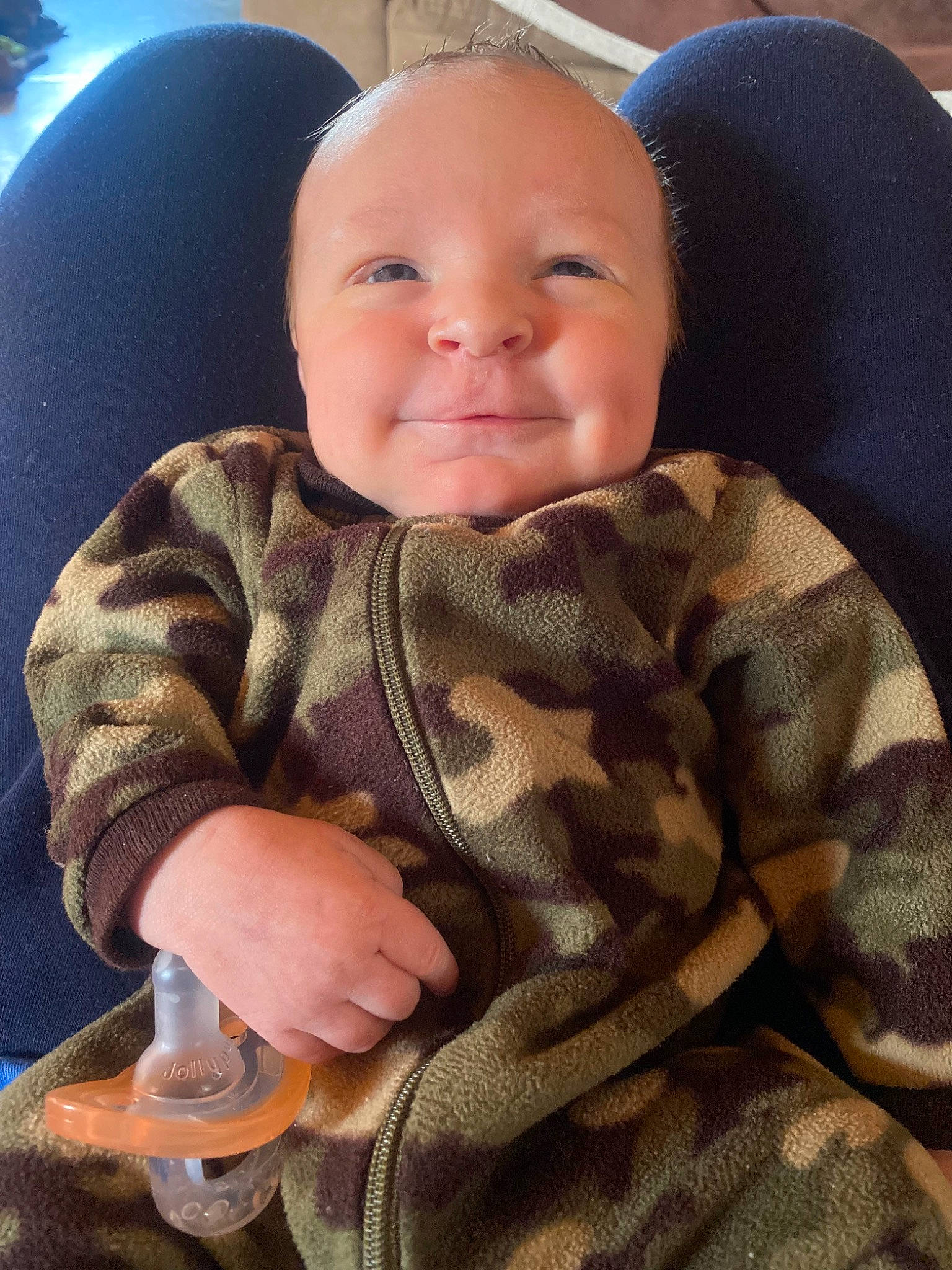 Gunner is registered to the contest to win money with this photo: baby, baby_toddler_clothing, car_seat, cheek, comfort, eye, face, finger, happy, head, iris, joy, lip, mouth, nose, person, plant, skin, sleeve, smile