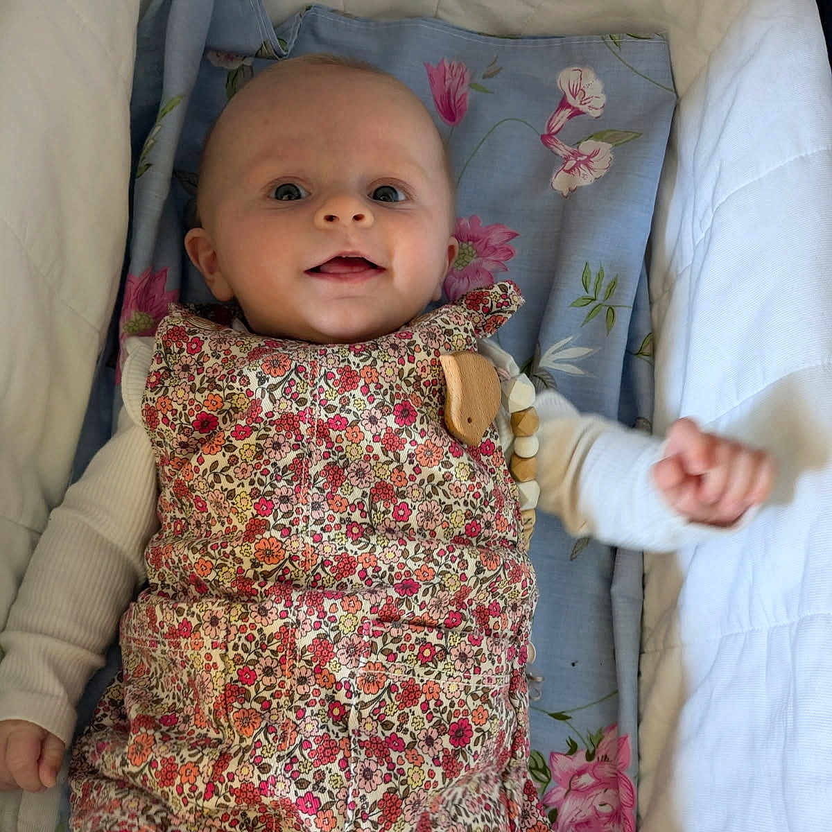 Lys participe au concours pour gagner de l'argent avec cette photo : baby, blue_blanket, child, colorful_clothing, comfort, cozy, cute, face, floral_dress, happy, indoors, infant, lying_down, person, portrait, small_hand, smiling, soft_lighting, white_cradle, wooden_beads