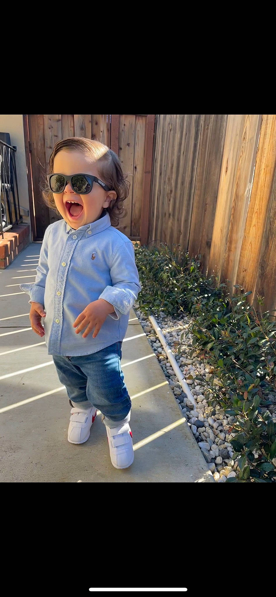 Lionel is registered to the contest to win money with this photo: baby_toddler_clothing, clothing, cool, denim, electric_blue, eyewear, fence, footwear, glasses, happy, home_fencing, person, plant, shoulder, sleeve, smile, street_fashion, sunglasses, toddler, vision_care