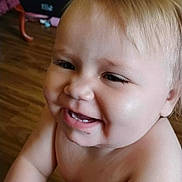 Gracelyn joined the competition — help win amazing prizes! baby, child, smiling, blond_hair, crawling, indoors, wooden_floor, living_room, furniture, person, happy, cute, skin, face, head, cheeks, expression, playful, home, infant