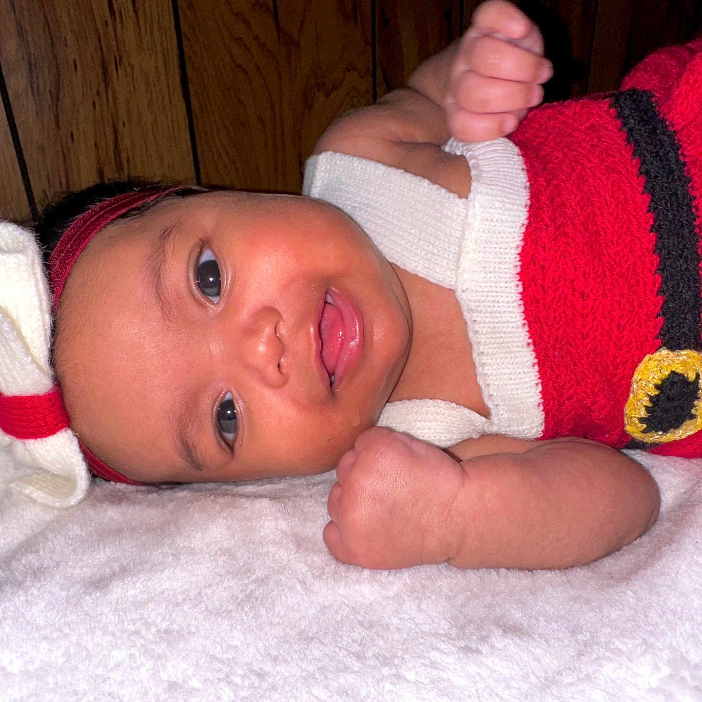 Zhamira joined the competition — help win amazing prizes! baby, blanket, child, cozy, cute, face, fist, happy, headband, indoors, infant, knitwear, lying_down, portrait, red_clothing, skin, smile, warm, wooden_wall, young