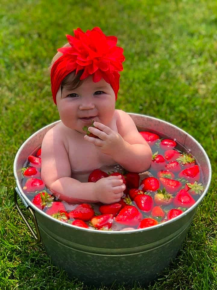 Camille is registered to the contest to win money with this photo: baby, baby_products, baby_toddler_clothing, child, costume_hat, fashion_accessory, flower, fun, grass, happy, headband, headpiece, headwear, people_in_nature, person, petal, pink, plant, red, smile
