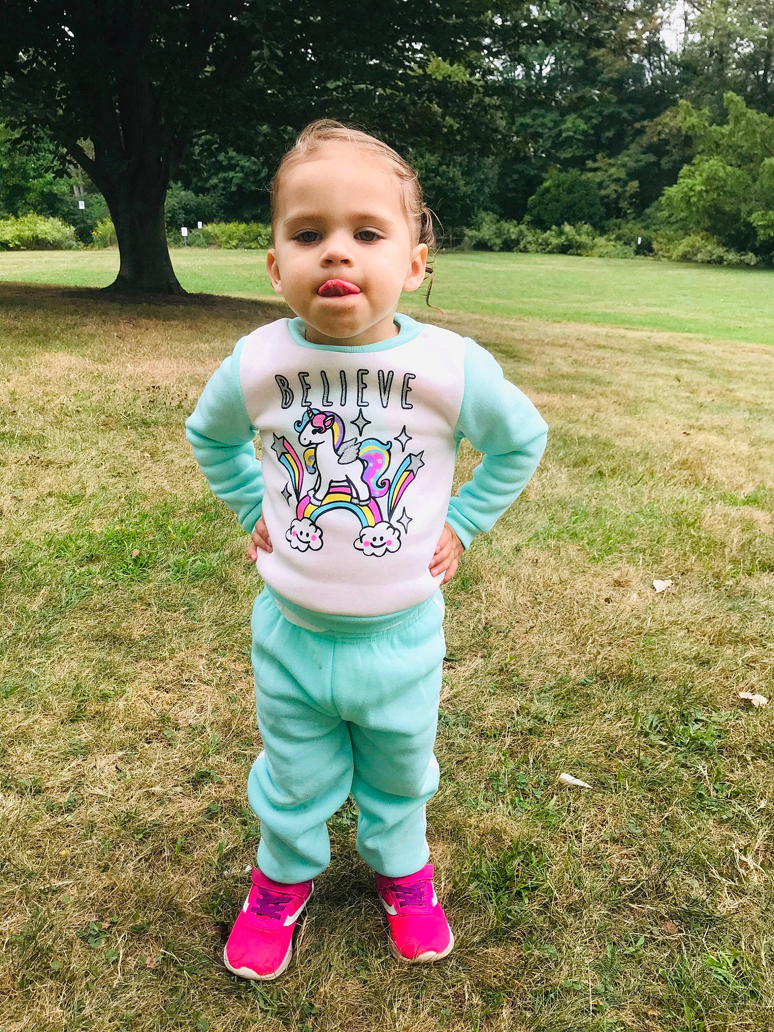 Harmony is registered to the contest to win money with this photo: baby, baby_toddler_clothing, child, cool, face, grass, green, head, outerwear, people, person, pink, skin, sleeve, smile, standing, summer, t_shirt, toddler, tree