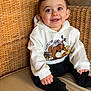 Tiago a rejoint le concours — aidez-le/la à gagner de superbes lots ! baby, child, smiling, hoodie, bear_design, sitting, wicker_chair, cushion, indoor, cozy, happy, person, clothing, cute, portrait, black_pants, young_child, infant, casual_wear, comfortable