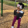 toddler, child, swing, playground, pacifier, headband, bow, outdoor, grass, trees, woodchips, shoes, pants, shirt, happy, park, person, daytime, recreation, fun