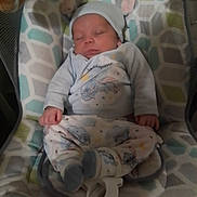 Jason is registered to the contest to win money with this photo: baby, sleeping, pajamas, baby_seat, infant, clothing, hat, cute, peaceful, indoor, child, soft_lighting, patterned, comfort, resting, newborn, cozy, small, toddler, person