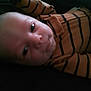 Jason is registered to the contest to win money with this photo: baby, infant, face, person, clothing, striped, orange, black, eyes, skin, head, portrait, cute, lying_down, indoors, child, young, expression, close-up, sleepy