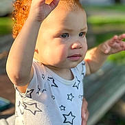 Shaya joined the competition — help win amazing prizes! toddler, child, curly_hair, red_hair, star_pattern, shirt, outdoor, sunlight, portrait, face, hands, expression, young_child, person, nature, bench, blurred_background, cute, innocent, daylight