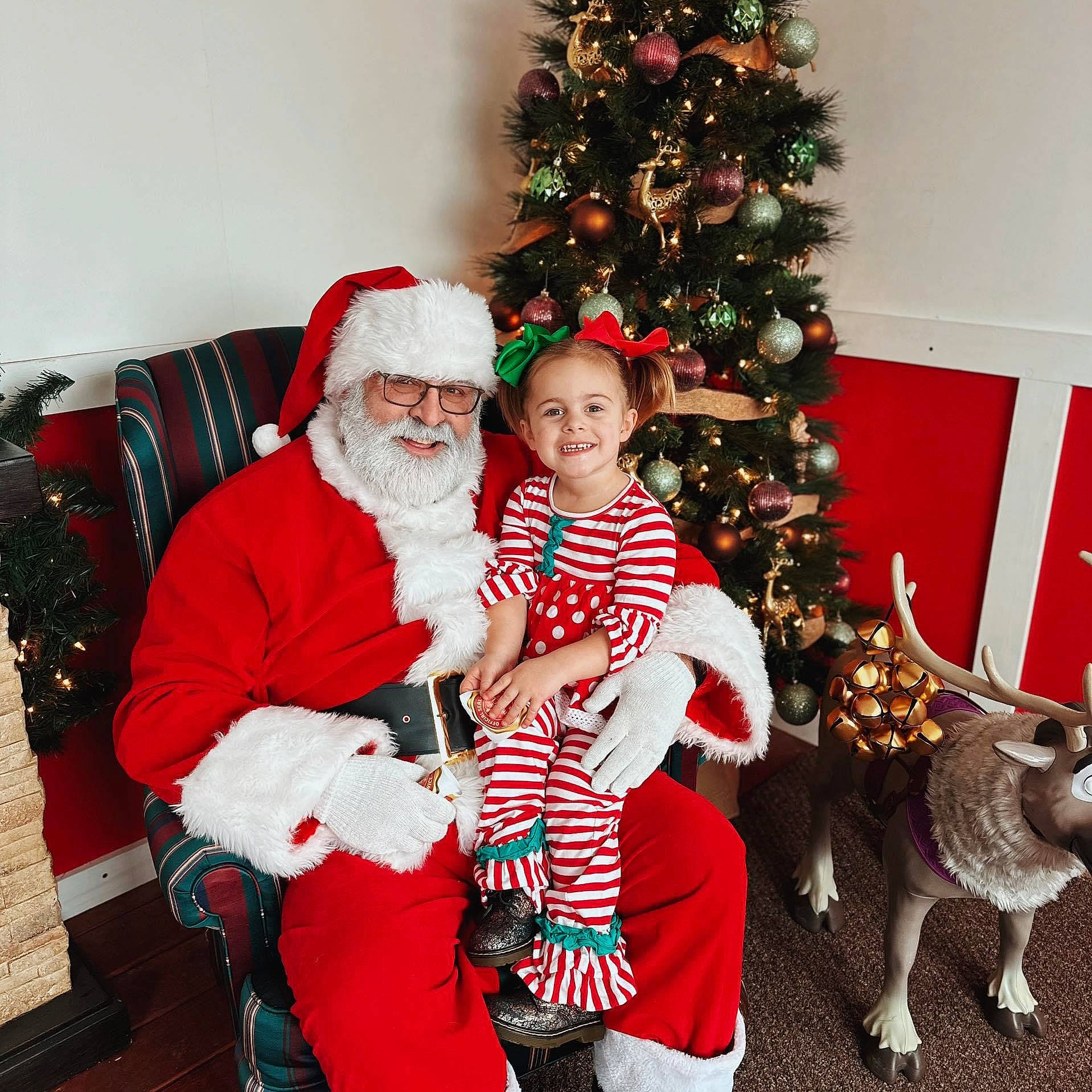 Bella is registered to the contest to win money with this photo: christmas, christmas_decoration, christmas_eve, christmas_ornament, christmas_tree, event, fur, happy, hat, headwear, holiday, holiday_ornament, joy, lap, person, red, santa_claus, smile, toddler, tradition