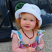 Victoire a rejoint le concours — aidez-le/la à gagner de superbes lots ! toddler, child, hat, red_hair, blue_eyes, necklace, dress, rock, outdoor, sunhat, smile, portrait, person, cute, young_child, summer, colorful_clothing, skin, hand, nature