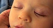 Lilly is registered to the contest to win money with this photo: baby, blanket, cheeks, close_up, clothing, eyelashes, eyes_closed, face, hand, indoor, infant, lips, nose, peaceful, photography, portrait, resting, sleeping, sleepy, striped_shirt