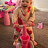 Lilly is registered to the contest to win money with this photo: activity_table, barefoot, carpet, child, face, floral_clothing, happy, home, indoor, pink, playroom, playtime, portrait, ride_on_toy, sitting, smiling, standing, stuffed_animal, toddler, toy