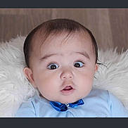 Liam is registered to the contest to win money with this photo: baby, infant, face, blue_bow, clothing, wide_eyes, expression, fluffy, white_background, portrait, cute, child, indoor, head, skin, person, young, looking, sitting, baby_girl_or_boy