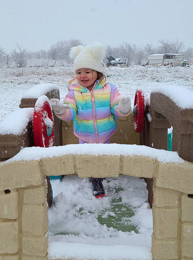 Aurora is registered to the contest to win money with this photo: baby_toddler_clothing, beanie, freezing, frost, headwear, hood, ice, ice_cap, person, play, playing_in_the_snow, precipitation, snow, winter
