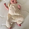 baby, infant, smiling, laughing, headband, clothing, onesie, barefoot, mattress, bed, textured, happy, cute, child, person, indoor, newborn, small, lying_down, joyful