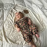 Magnolia is registered to the contest to win money with this photo: baby, infant, child, romper, headband, floral_pattern, blanket, bed, white, wooden_sign, three_months, lying_down, curious, soft_texture, comfort, indoor, person, cute, newborn, portrait