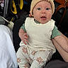 Magnolia is registered to the contest to win money with this photo: baby, infant, knit_hat, pom_pom, white_sweater, patterned_pants, socks, car_interior, car_seat, steering_wheel, hand, curious_expression, close_up, person, child, casual_clothing, seatbelt, brown_bag, toy, indoor