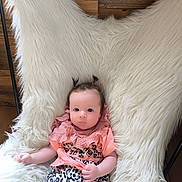 Adriana a rejoint le concours — aidez-le/la à gagner de superbes lots ! baby, infant, child, cute, pigtails, fluffy_chair, leopard_print, pink_top, wooden_wall, indoor, portrait, sitting, clothing, person, young_child, cozy, soft_texture, relaxed, bright_eyes, casual