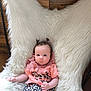 baby, infant, child, cute, pigtails, fluffy_chair, leopard_print, pink_top, wooden_wall, indoor, portrait, sitting, clothing, person, young_child, cozy, soft_texture, relaxed, bright_eyes, casual