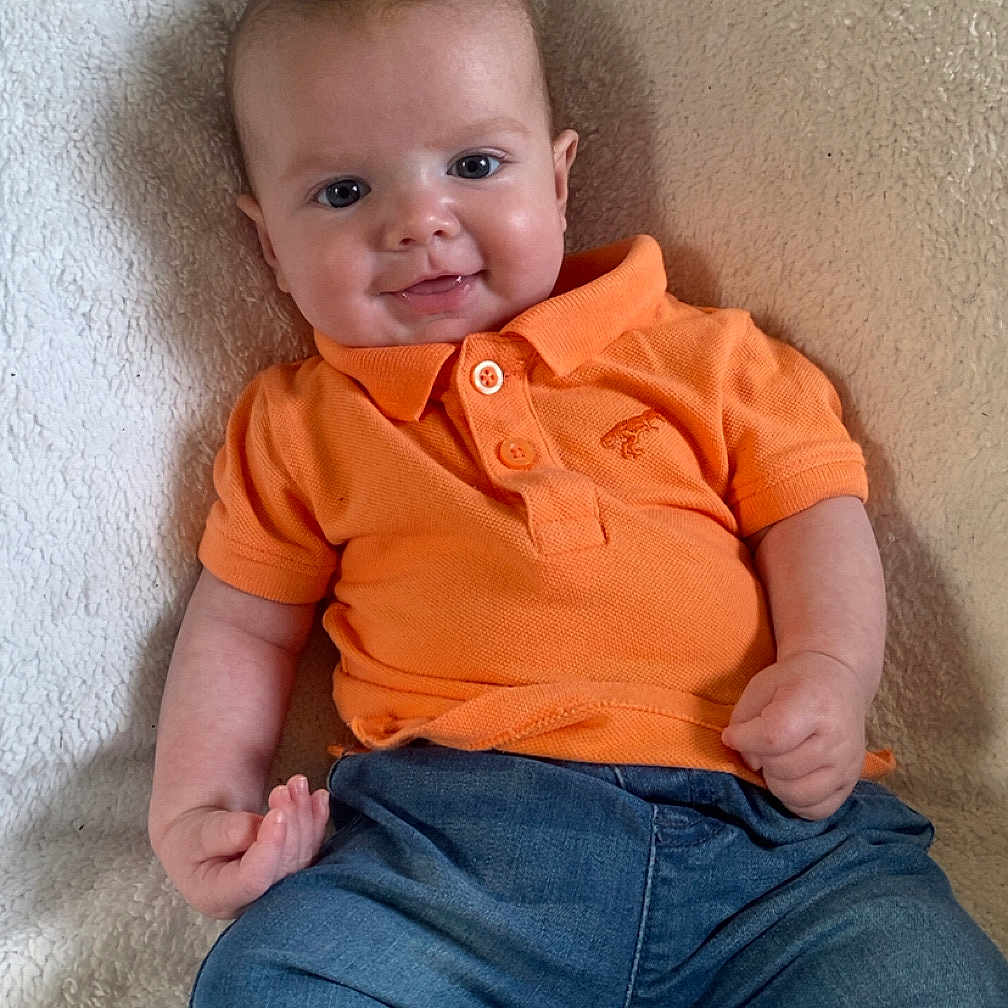 Vinny-Dean joined the competition — help win amazing prizes! baby, blanket, casual, child, clothing, cozy, cute, denim_pants, face, feet, happy, indoor, infant, orange_shirt, person, portrait, sitting, smile, striped_socks, young_child