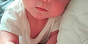 Roman is registered to the contest to win money with this photo: baby, blanket, closeup, cute, expression, eyes, face, fist, hand, indoors, infant, lying_down, newborn, person, portrait, quilt, skin, soft_texture, white_clothing, young_child