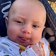 Dawson is registered to the contest to win money with this photo: baby, infant, face, tongue, onesie, animal_print, blanket, hand, outdoor, closeup, cute, expression, skin, head, person, child, smile, warm, young, cozy