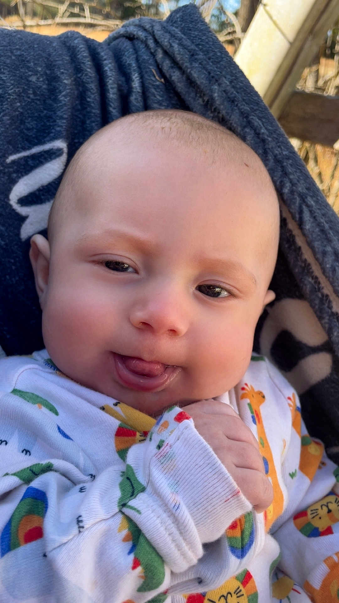 Dawson is registered to the contest to win money with this photo: baby, infant, face, tongue, onesie, animal_print, blanket, hand, outdoor, closeup, cute, expression, skin, head, person, child, smile, warm, young, cozy