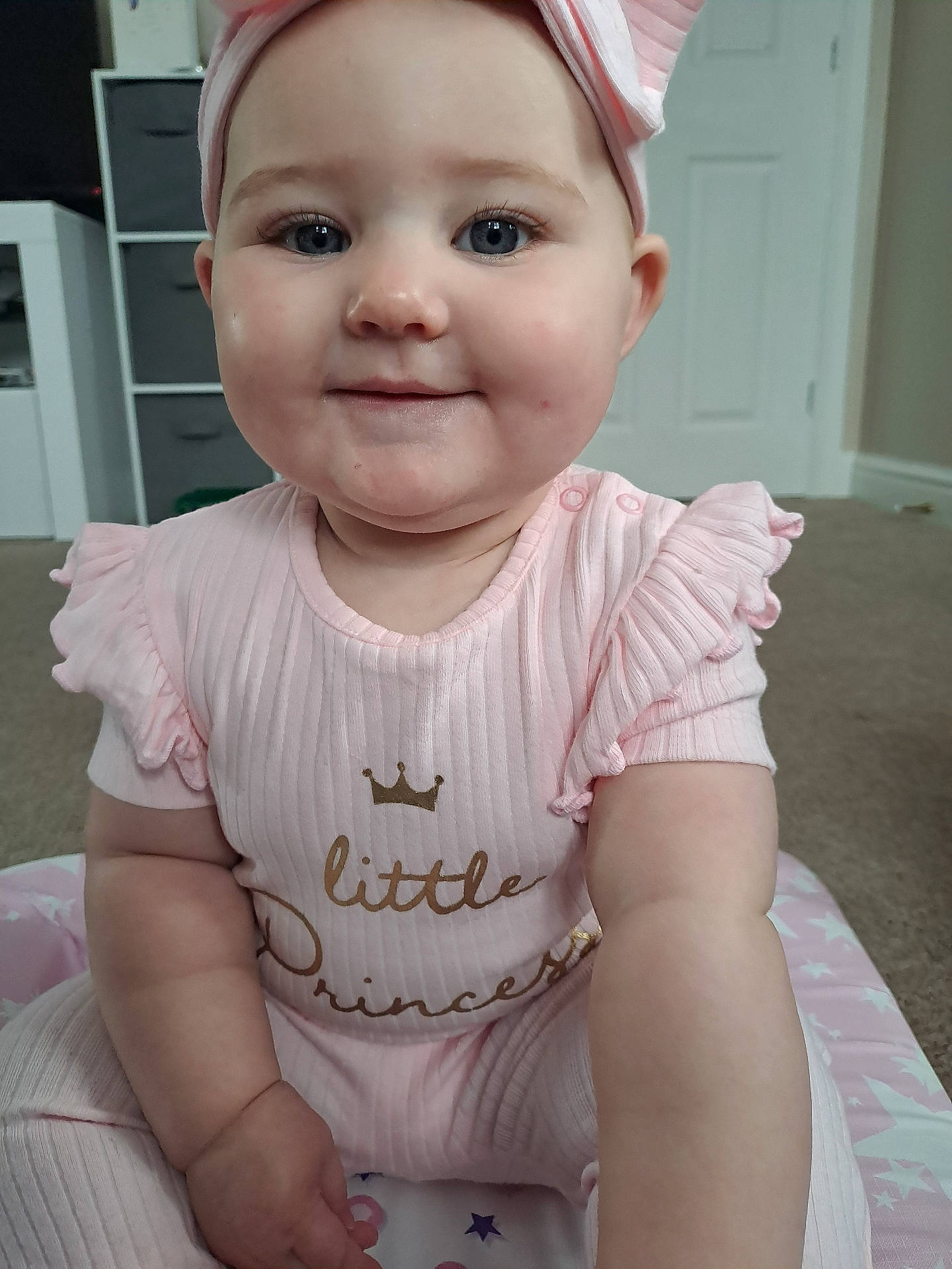 Layla joined the competition — help win amazing prizes! architecture, baby, building, cap, clothing, dress, face, furniture, happy, hat, head, indoors, livingroom, person, photography, portrait, room, sitting, smile, t_shirt