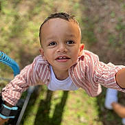 Eziel participe au concours pour gagner de l'argent avec cette photo : child, smiling, outdoor, grass, shirt, white_tshirt, striped_shirt, happy, face, person, young_child, portrait, daylight, casual_clothing, cute, boy, expression, looking_up, sunlight, playful